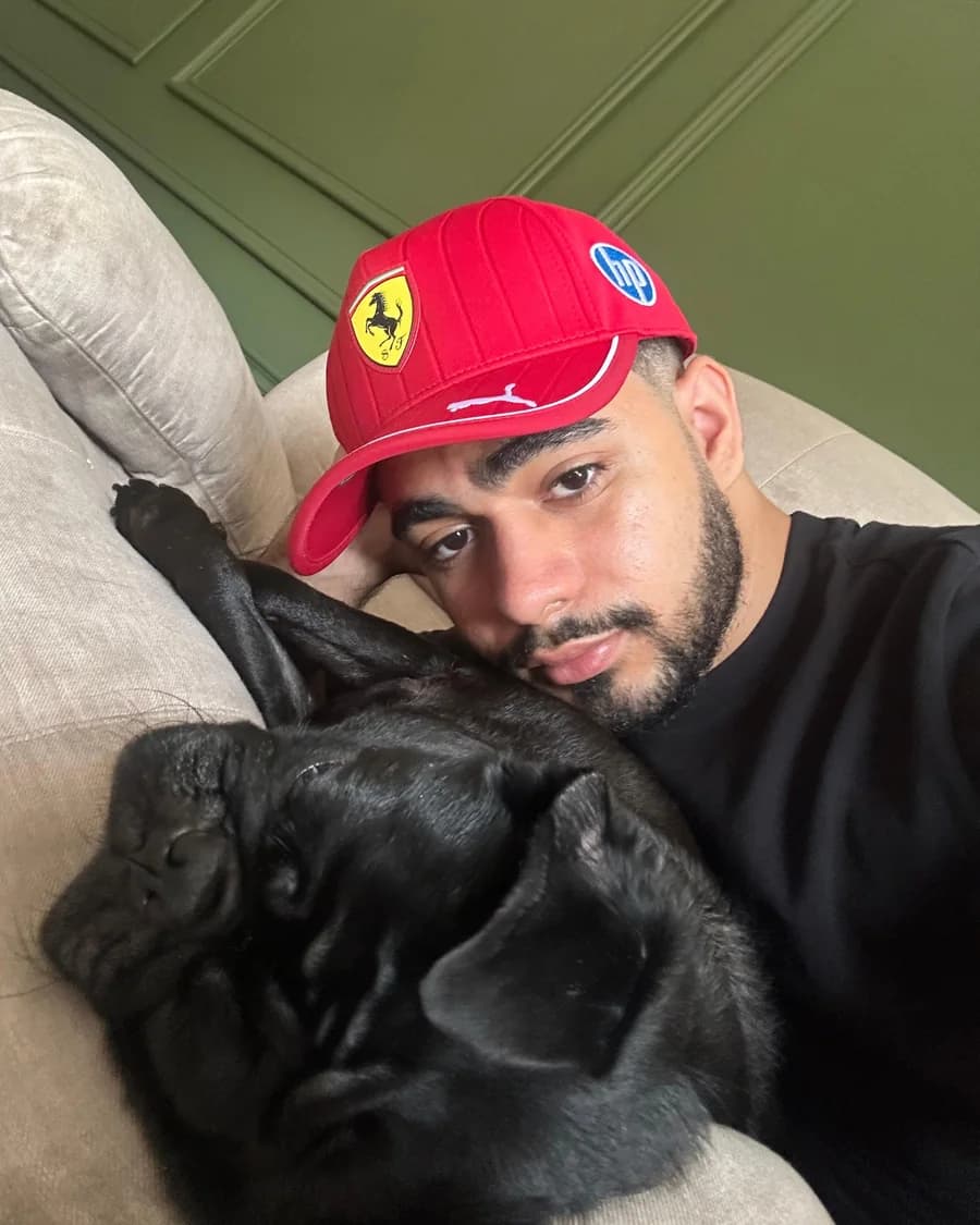 Alex M. Rodriguez in a red cap, resting beside a sleeping black pug